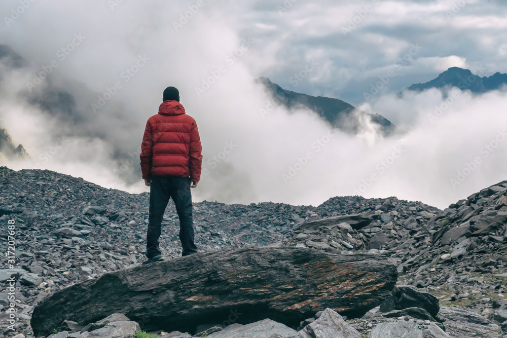 Above clouds. A hiker looking at dramatic cloudy high mountain landscape.