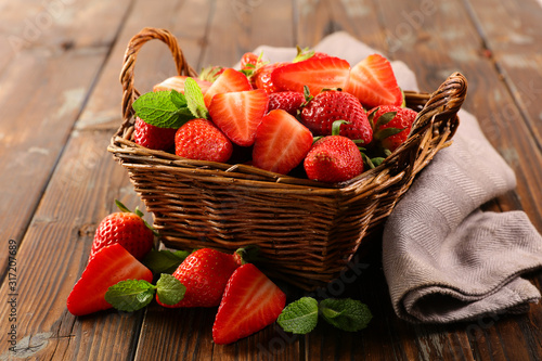 wicker basket with juicy strawberry on wood background photo