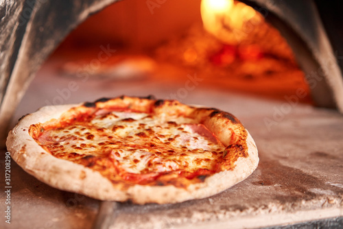 Fotomurale Baked tasty margherita pizza in Traditional wood oven in Naples restaurant, Italy