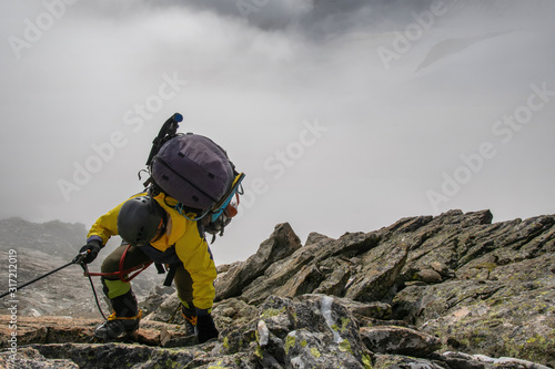 A mountain climber climb the mountain pass on the background of clouds..