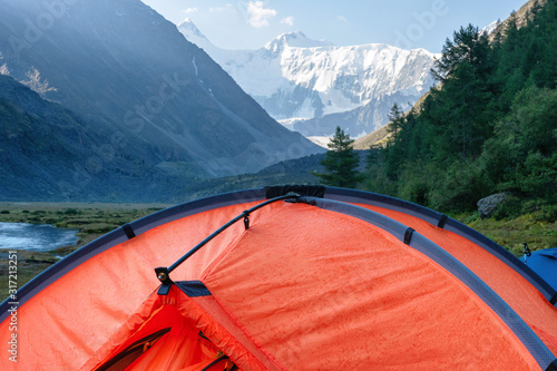 After the rain. Orange tent with rain drops on the background of Belukha Mountain. Upper reach of Akkem river, Altai mountains, Altai Republic, Siberia, Russia. photo