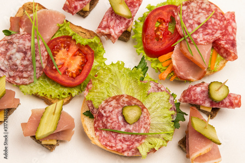 Sandwich with ham, salami, cheese and lettuce on a white background. Copy space, white background.