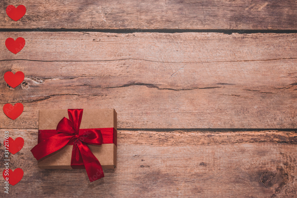 Paper hearts and a craft present with red ribbon on a wooden background. Top side angle view, flat lay. Valentines day concept. Copyspace. Paper hearts and a craft present with red ribbon on a wooden background. Top side angle view, flat lay. Valentines day concept. Copyspace.