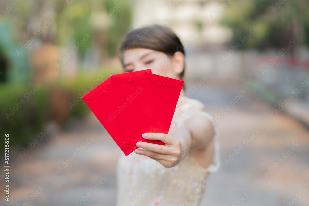 Asian women wear cream-colored Chinese dresses with red envelopes on the front. With her face and body blurred and focus on the red envelope. Happy chinese new year. Asian women wear cream-colored Chinese dresses with red envelopes on the front. With her face and body blurred and focus on the red envelope. Happy chinese new year.