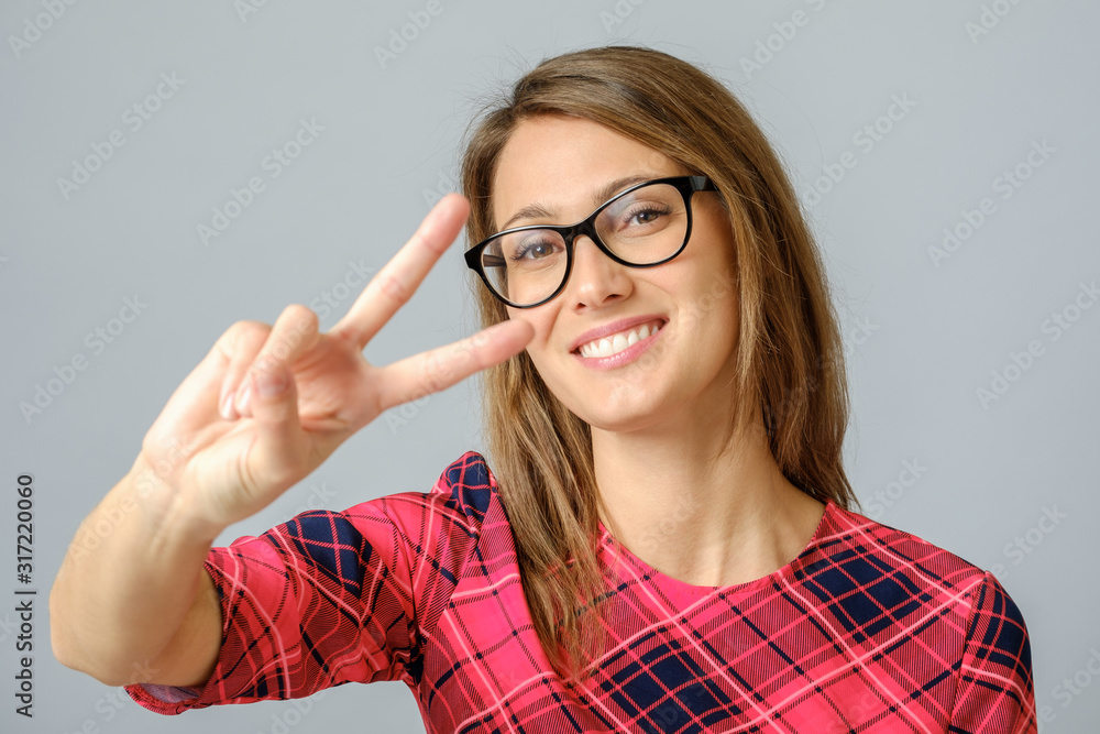 Cheerful woman showing peace sign with her fingers Cheerful woman showing peace sign with her fingers