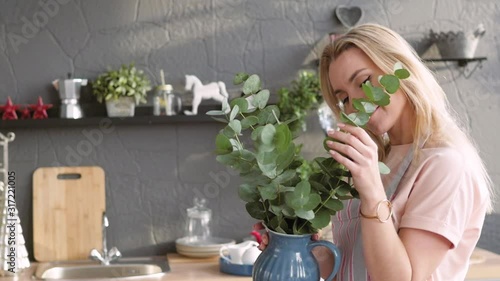 joyful woman makes a bouquet for table setting. The blonde is making a bouquet of eucalyptus. Festive table setting. Florist soborset bouquet on the table