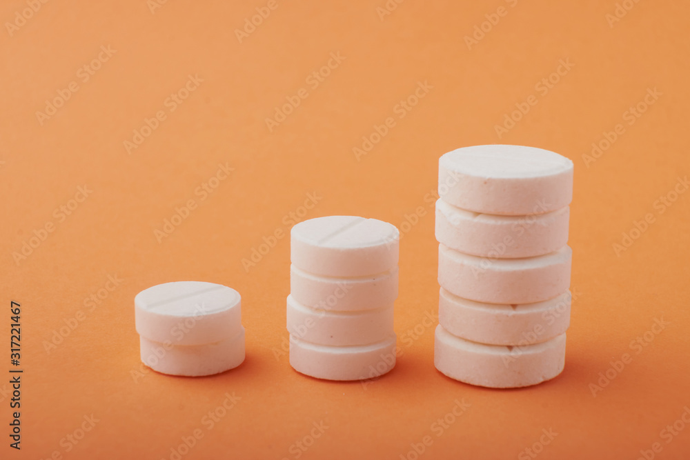 various white tablets on an orange background various white tablets on an orange background