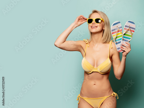 woman in yellow bikini and sunglasses with flip-flops