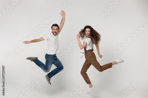 Joyful young man and happy millennial girl jumping high.