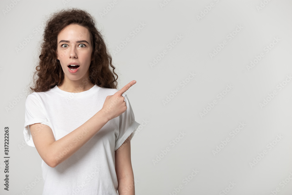 Surprised young girl standing aside, pointing finger to free space. Surprised young girl standing aside, pointing finger to free space.