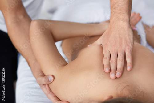 Young beautiful woman enjoying back and shouders massage in spa.Professional massage therapist is treating a female patient in apartment.Relaxation,beauty,body and face treatment concept.Home massage.
