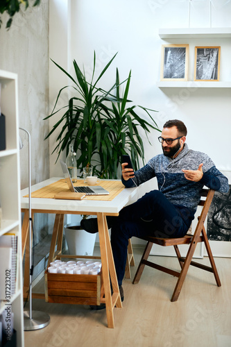 Attractive casual freelance businessman in the middle of video call in modern office.