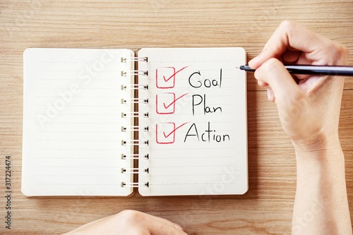 woman hand writing text goal plan action and checklist on notebook  photo