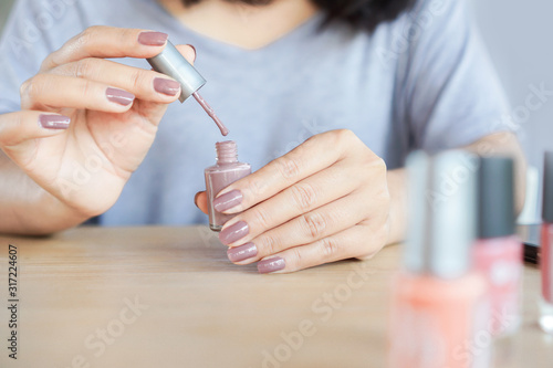closeup woman hand painting nail with vanish