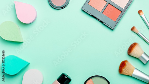 Beauty sponges, makeup brushes, various makeup products on pastel background, copy space, top view. Beauty background or cosmetics web banner frame. Beauty treatment, self care background overhead
