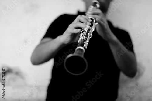 Vászonkép Grey scale shot of a person playing clarinet in front of a white wall