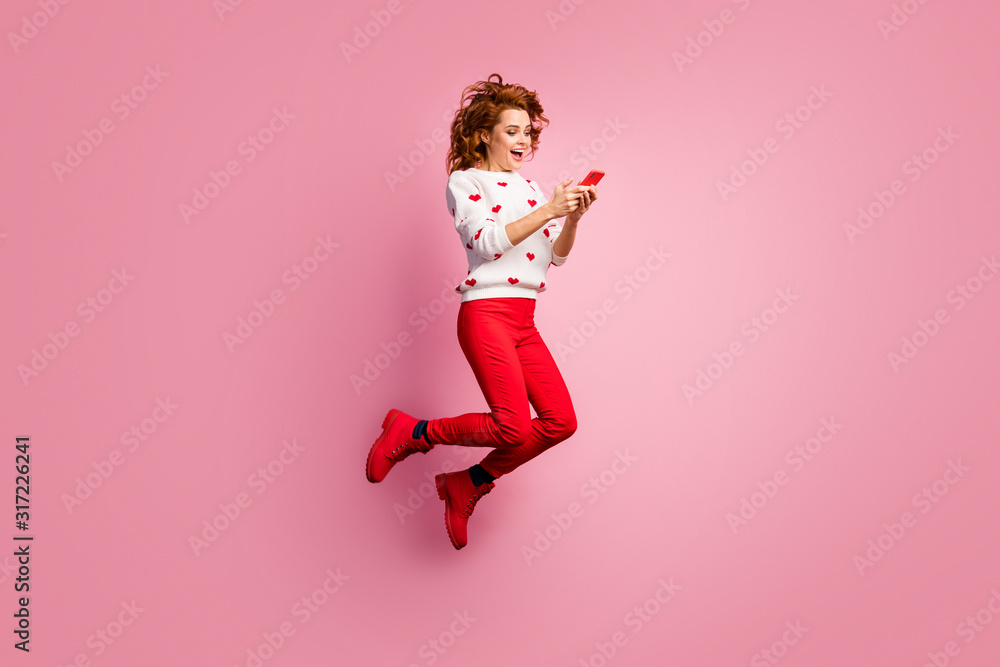 Full length body size view of nice attractive cheerful cheery foxy ginger wavy-haired girl blogger influencer jumping using cell 5g app blogging post like smm isolated on pink pastel color background