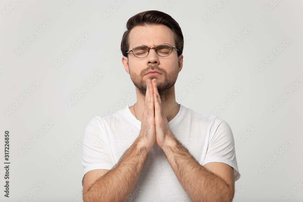 Head shot praying man isolated on grey studio background portrait. Head shot praying man isolated on grey studio background portrait.