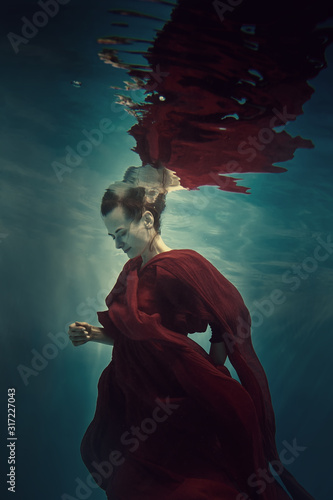 Portrait of a girl in a red dress under water