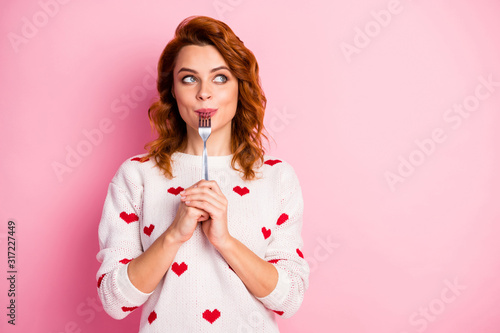 Close-up portrait of her she nice attractive pretty dreamy cheerful wavy-haired girl licking fork want wish desire tasty yummy meal temptation seduction isolated on pink pastel color background photo