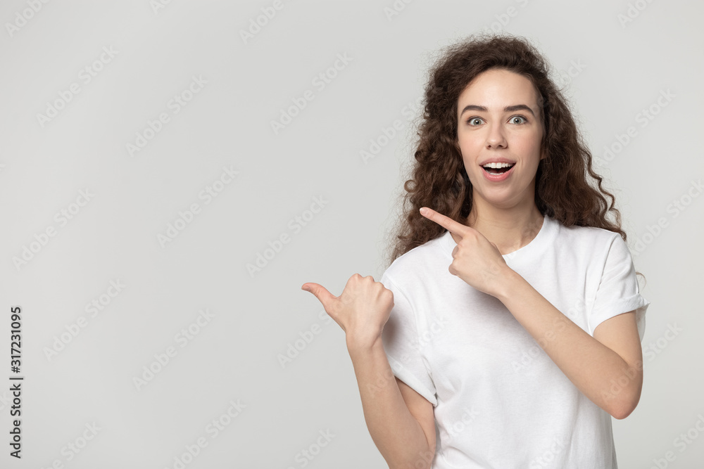 Amazed millennial girl pointing both hands at free copy space. Amazed millennial girl pointing both hands at free copy space.