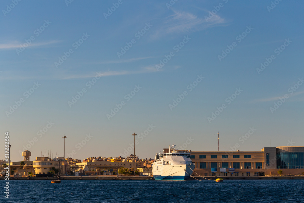Hurghada, Egypt, a city at sunset. View of the ancient city from the red sea. Panoramic view. A port with ships and a residential area with a mosque.