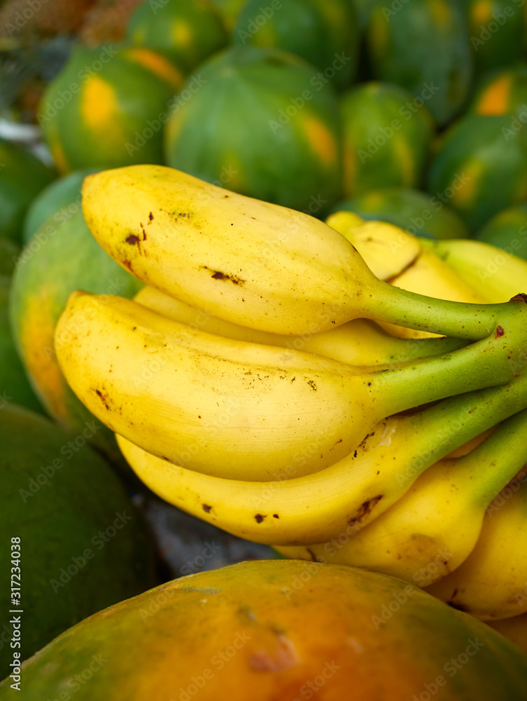 Close up picture of ripe bananas among papayas.