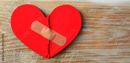 Obraz na płótnie Two parts of red broken wooden heart taped by a patch