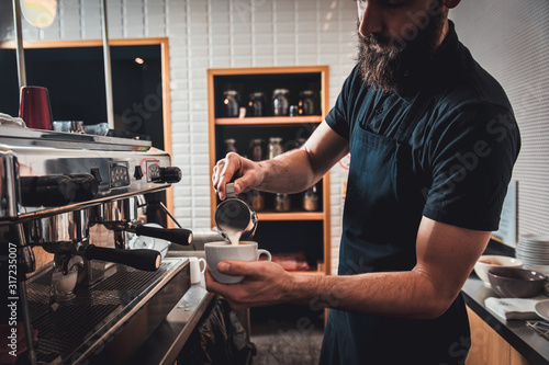 Barista preparing cappuccino on espresso machine for customer in coffee shop. photo