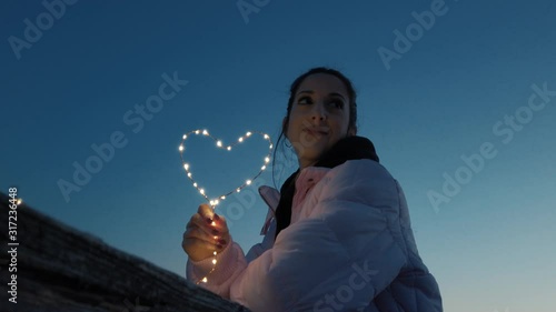 Simbolo del cuore tenuto in mano da una ragazza al tramonto. Concetto di san valentino. photo