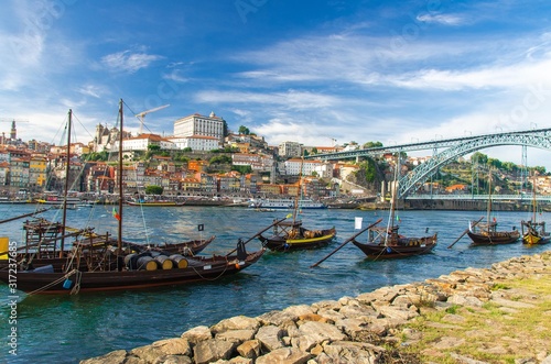 Portugal, city landscape Porto, wooden boats with wine port barrels close up on Douro, panoramic view of the old town Porto,  The Eiffel Bridge view, Ponte Dom Luis, Porto in summer, colored houses © Aliaksandr