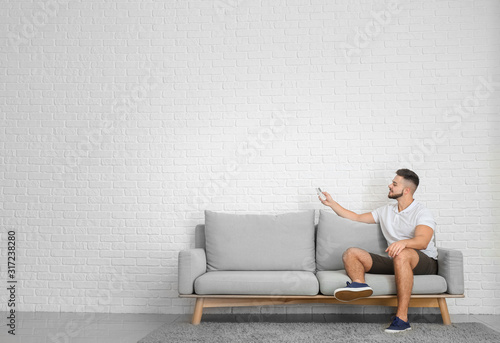 Canvas Print Young man switching on air conditioner at home
