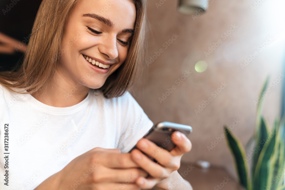 Fototapeta premium Photo of joyful young woman using cellphone and smiling
