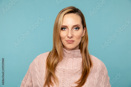 Portrait of handsome woman in the sweater posing on the blue background