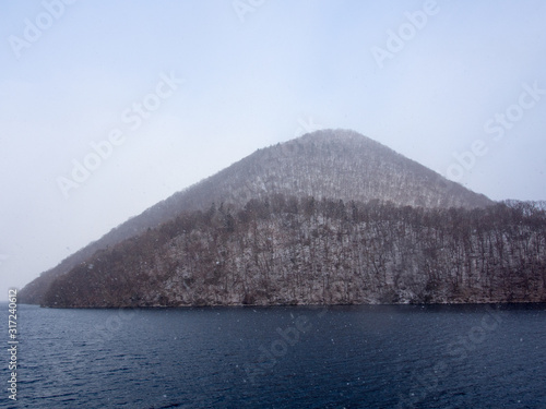 View of Oshima in Lake Toya , Hokkaido while snow is falling in the foreground photo