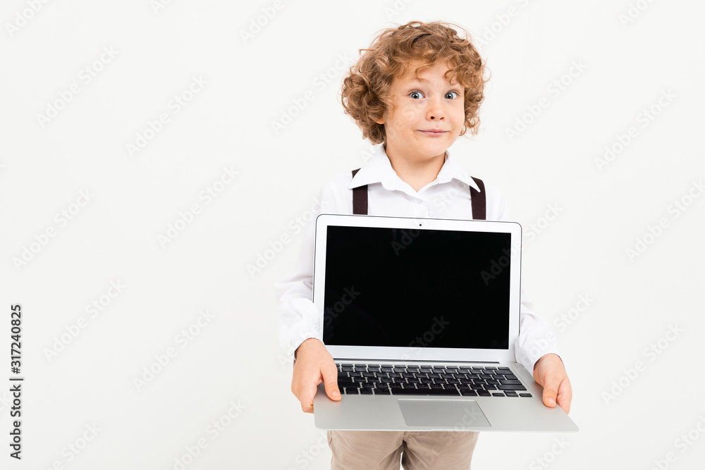 Beautiful boy with curly hair in white shirt, brown hat, glasses with black suspenders holds a laptop isolated on white background Beautiful boy with curly hair in white shirt, brown hat, glasses with black suspenders holds a laptop isolated on white background