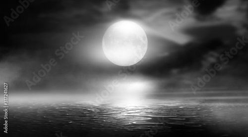 Dramatic black and white background. Cloudy night sky, moonlight, reflection on the pavement. Smoke and fog on a dark street at night.