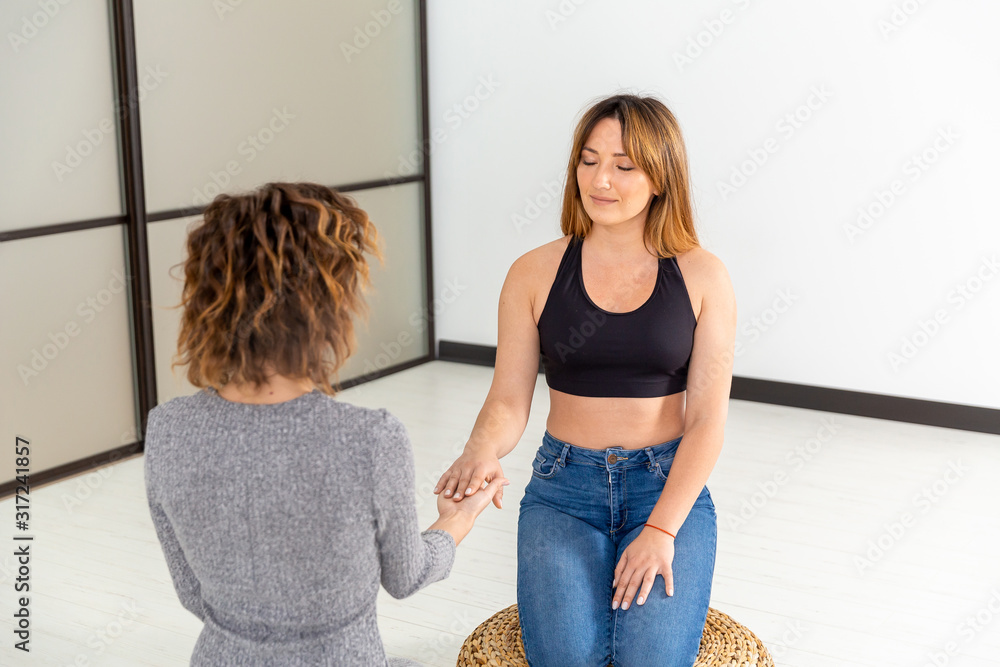 Fototapeta premium Wellness healthy concept. Meditation of two women on the floor. Relax and zen in the white room. Body care