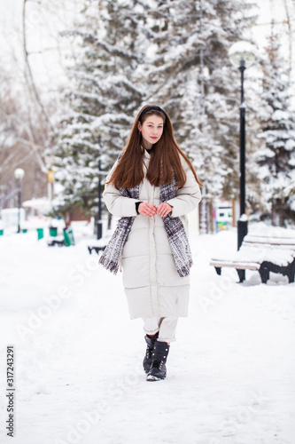 Young brunette woman in white down jacket in winter street