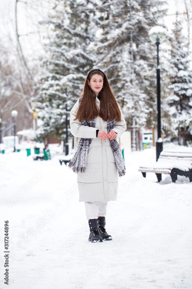 Young brunette woman in white down jacket in winter street Young brunette woman in white down jacket in winter street