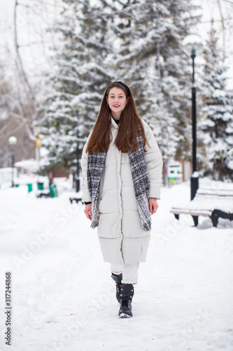 Young brunette woman in white down jacket in winter street