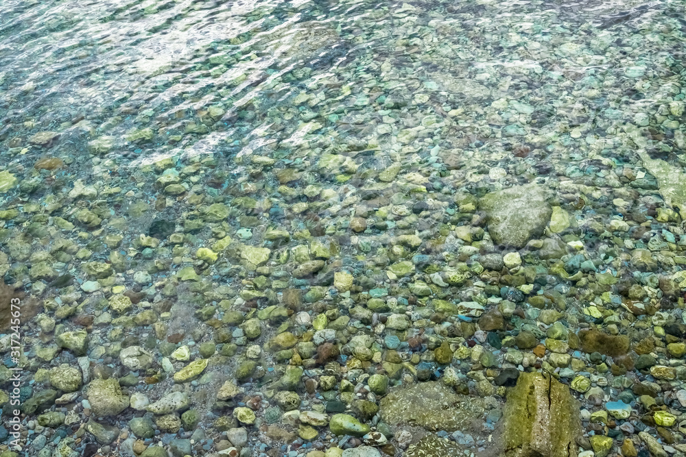 Abstract marine background with water covering stones and pebbles. Sea calm