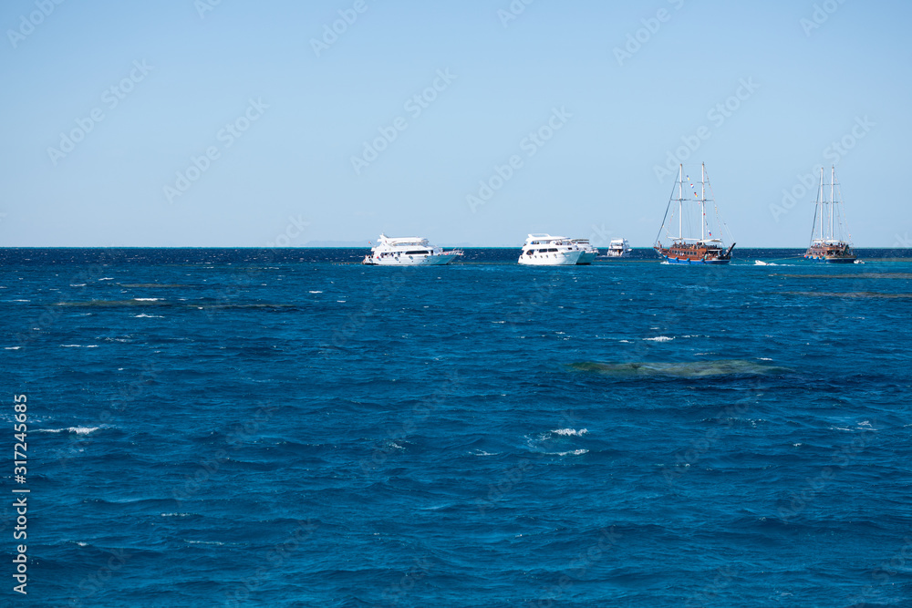 Dark-blue and wavy surface of the Red Sea with ships in the distance