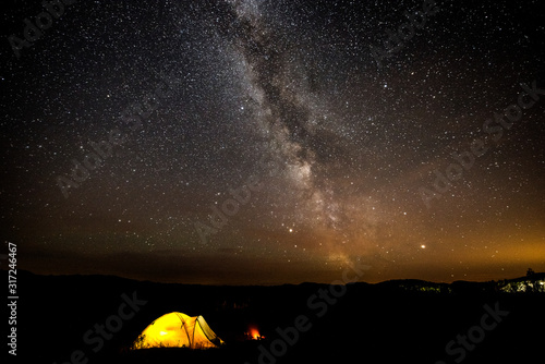 night, the milky way, a very starry sky and a tent standing next to a fire