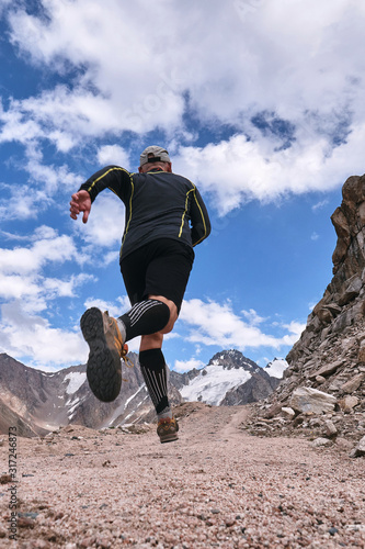 Closeup of feet with running shoes of a trailrunner man running in the mountains trail