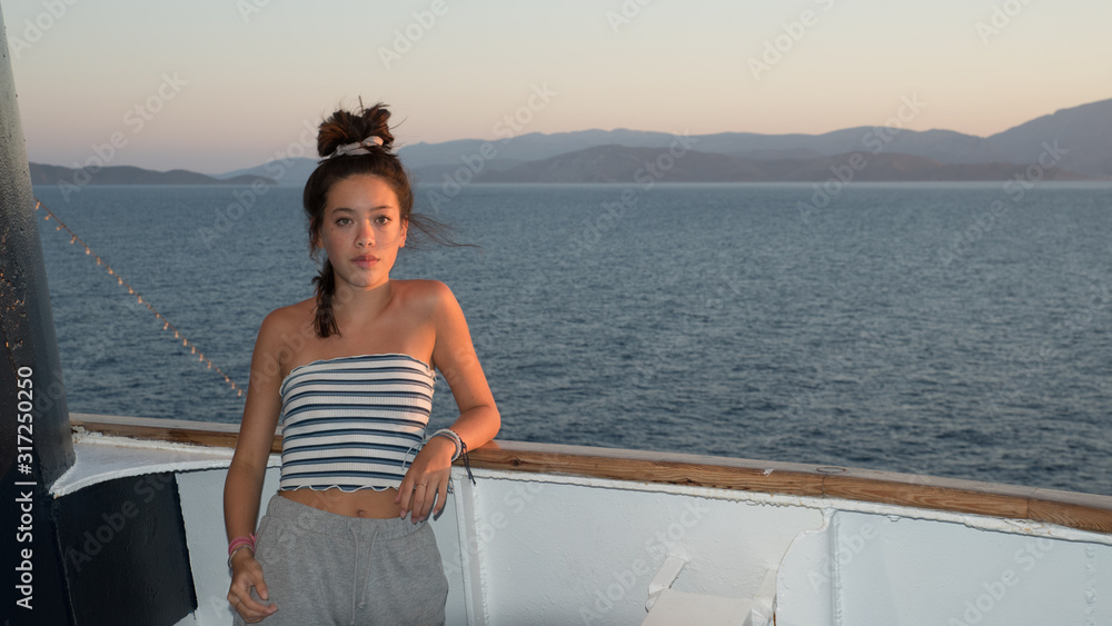 Closeup of Asian teen in striped tube top leaning against railing