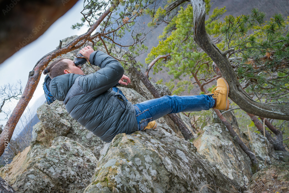 Naklejka premium Traveler with monocle sitting on a large branch of conifer and looks into the distance.