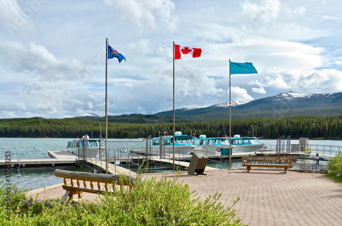 The picturesque mountain Maligne Lake in the Jasper National Park. A pier with boats on the lake and a sunny summer day