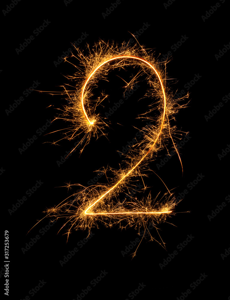 Digit 2 or two made of bengal fire, sparkler fireworks candle isolated on a black background. Party dark backdrop. Digit 2 or two made of bengal fire, sparkler fireworks candle isolated on a black background. Party dark backdrop.