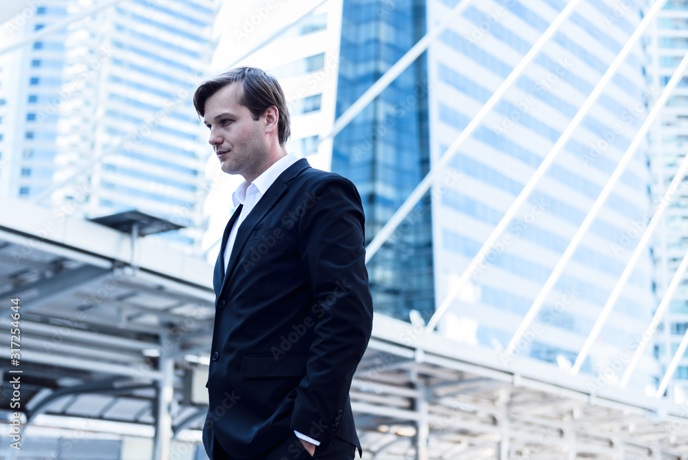 Portrait images of Cauacsian business man are standing on train station with blur tail building background, to people concept. Portrait images of Cauacsian business man are standing on train station with blur tail building background, to people concept.